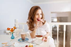 attractive young woman with long curly hair sitting and eating heart shaped cookies