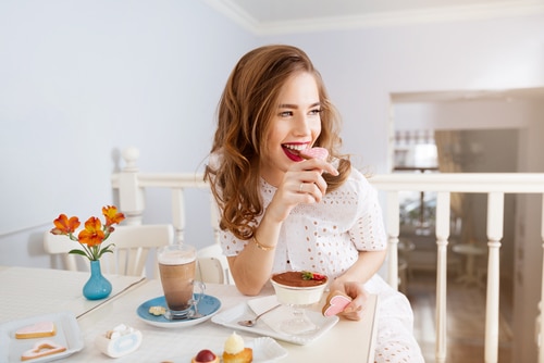 attractive young woman with long curly hair sitting and eating heart shaped cookies