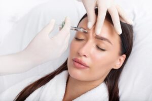 35 year old woman receives a Botox injection between her eyebrows to reduce the appearance of frown lines called dynamic wrinkles