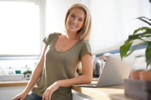 Woman in her 40s has youthful-looking breasts in her home office many years after breast lift surgery