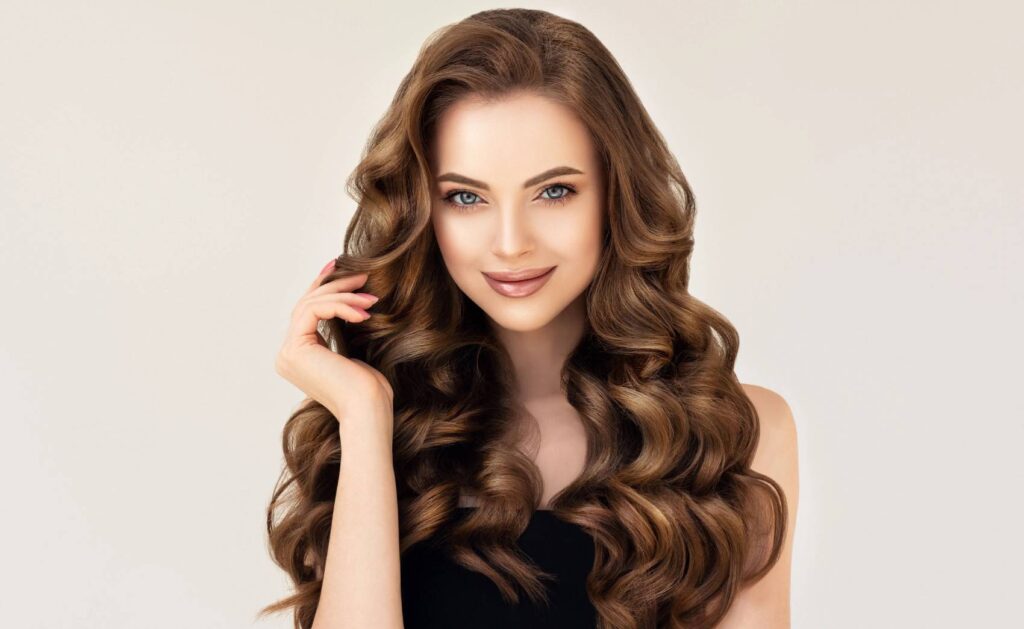 Woman with beautiful long curly hair. Pretty girl with perfect skin. Outdoor fashion portrait