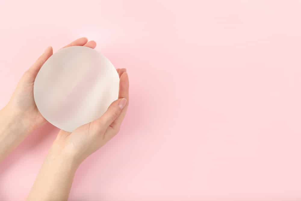 Female patient holds a breast implant in her hands.